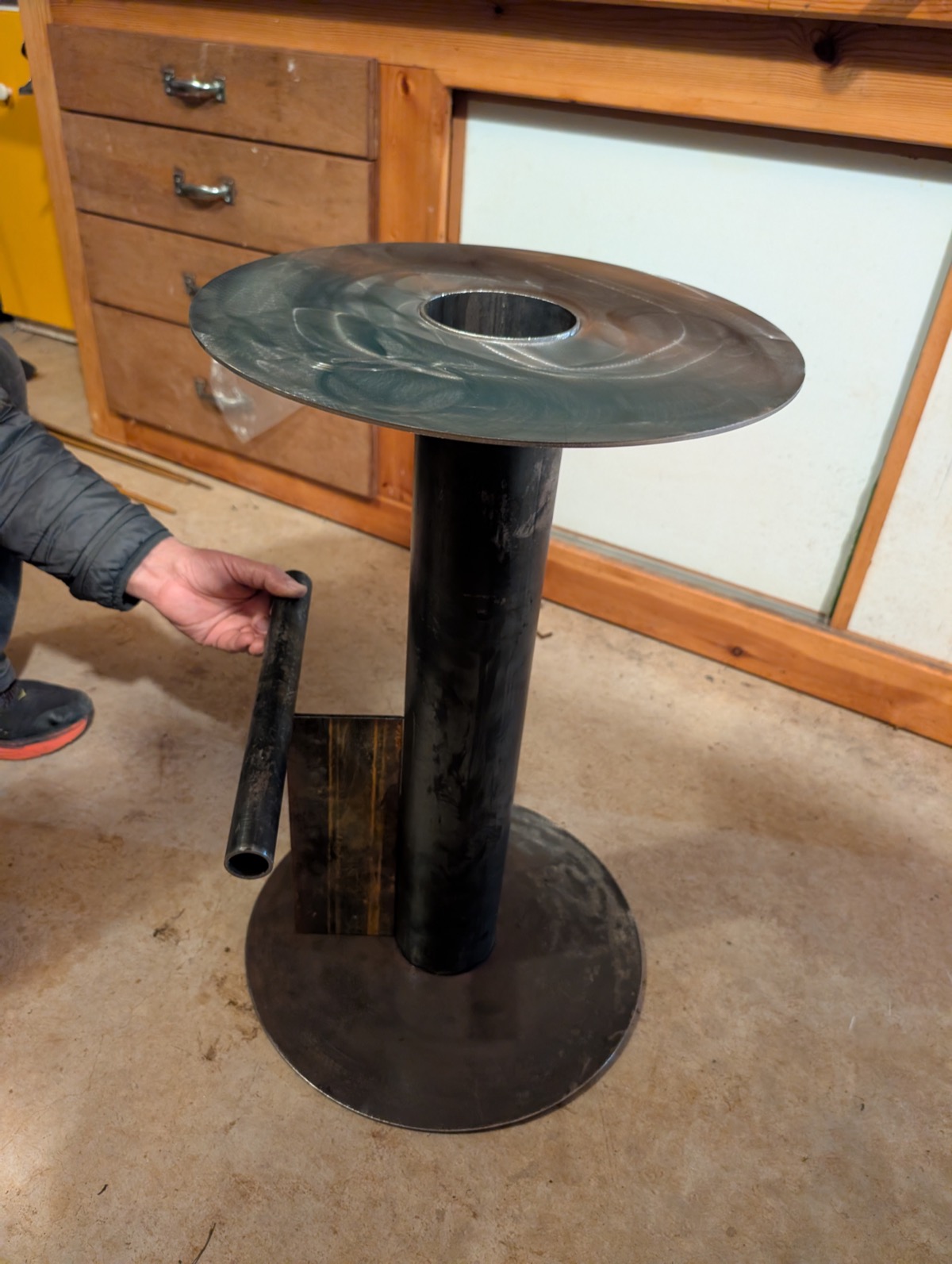 A raw steel tube held against the base to test footrest height and position