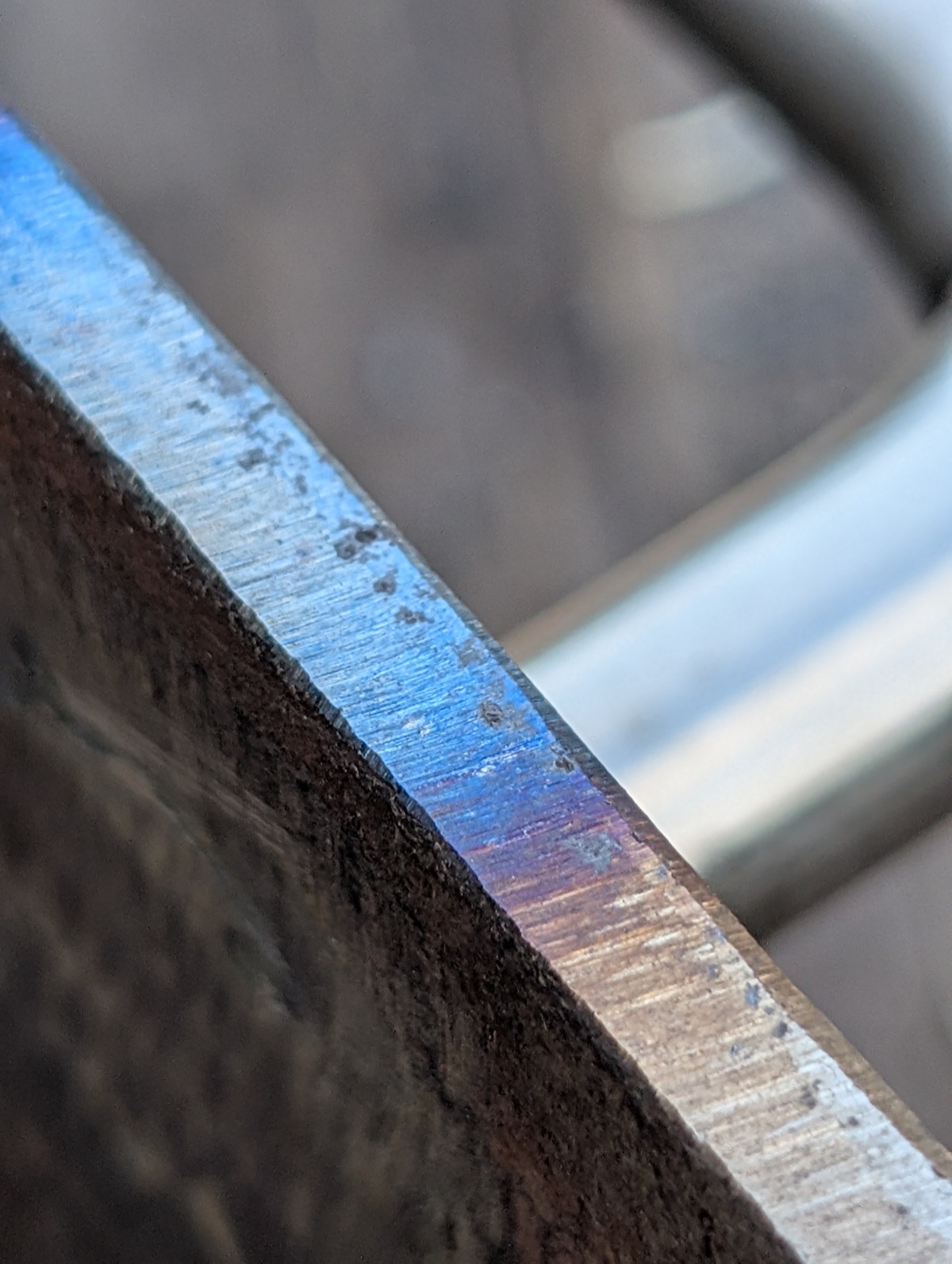 Close-up of a sanded steel edge showing blue and purple heat colours