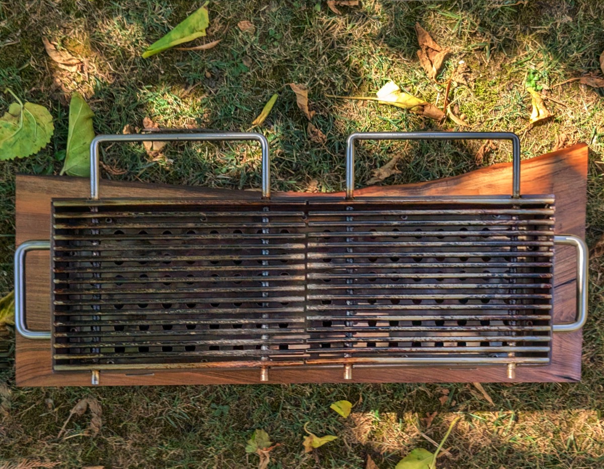 The finished grill seen from directly above, on grass scattered with leaves