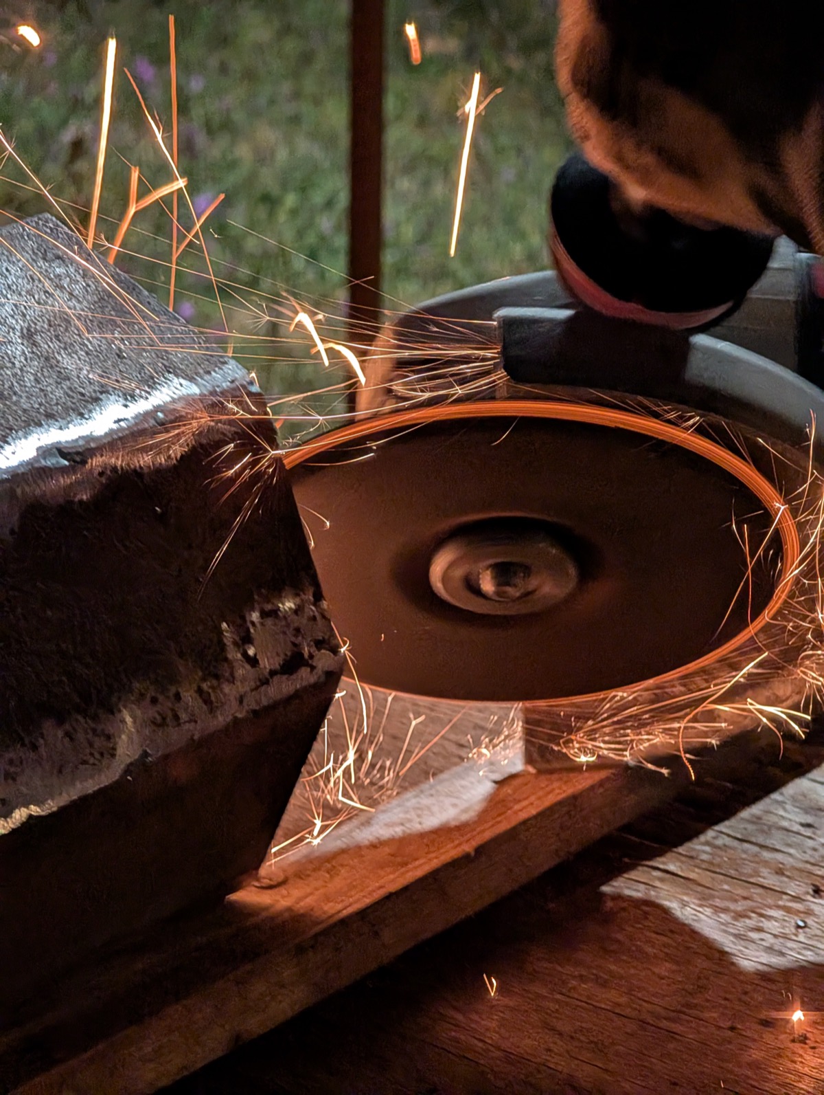 An angle grinder throwing sparks while smoothing a welded seam