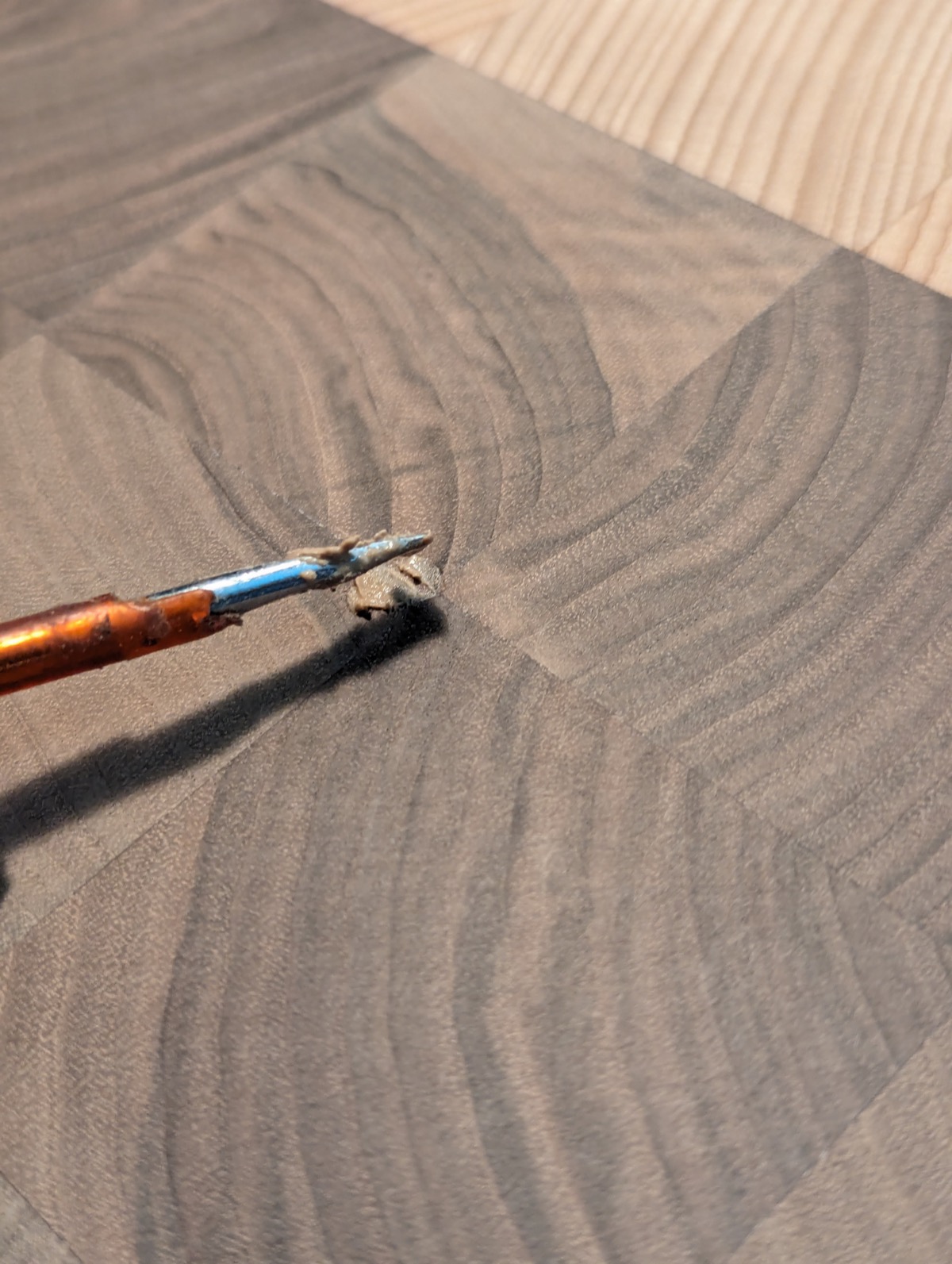 Close-up of a tool filling a small gap in the end grain with glue and dust