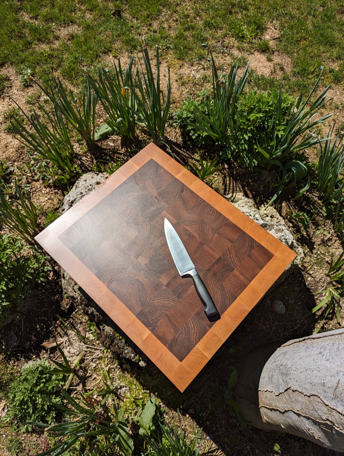 The finished board outdoors in the garden, a chef's knife resting on it