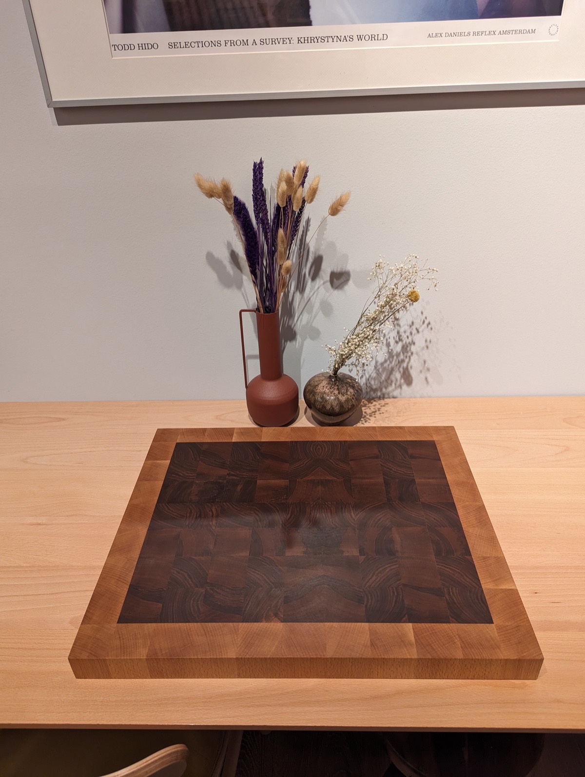 The finished board on a table indoors, dried flowers and a framed print behind