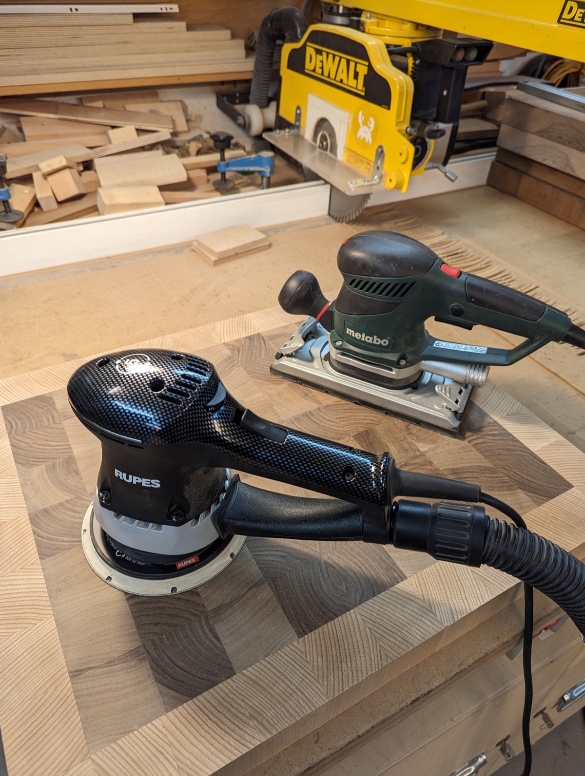 Two orbital sanders resting on the sanded end grain panel