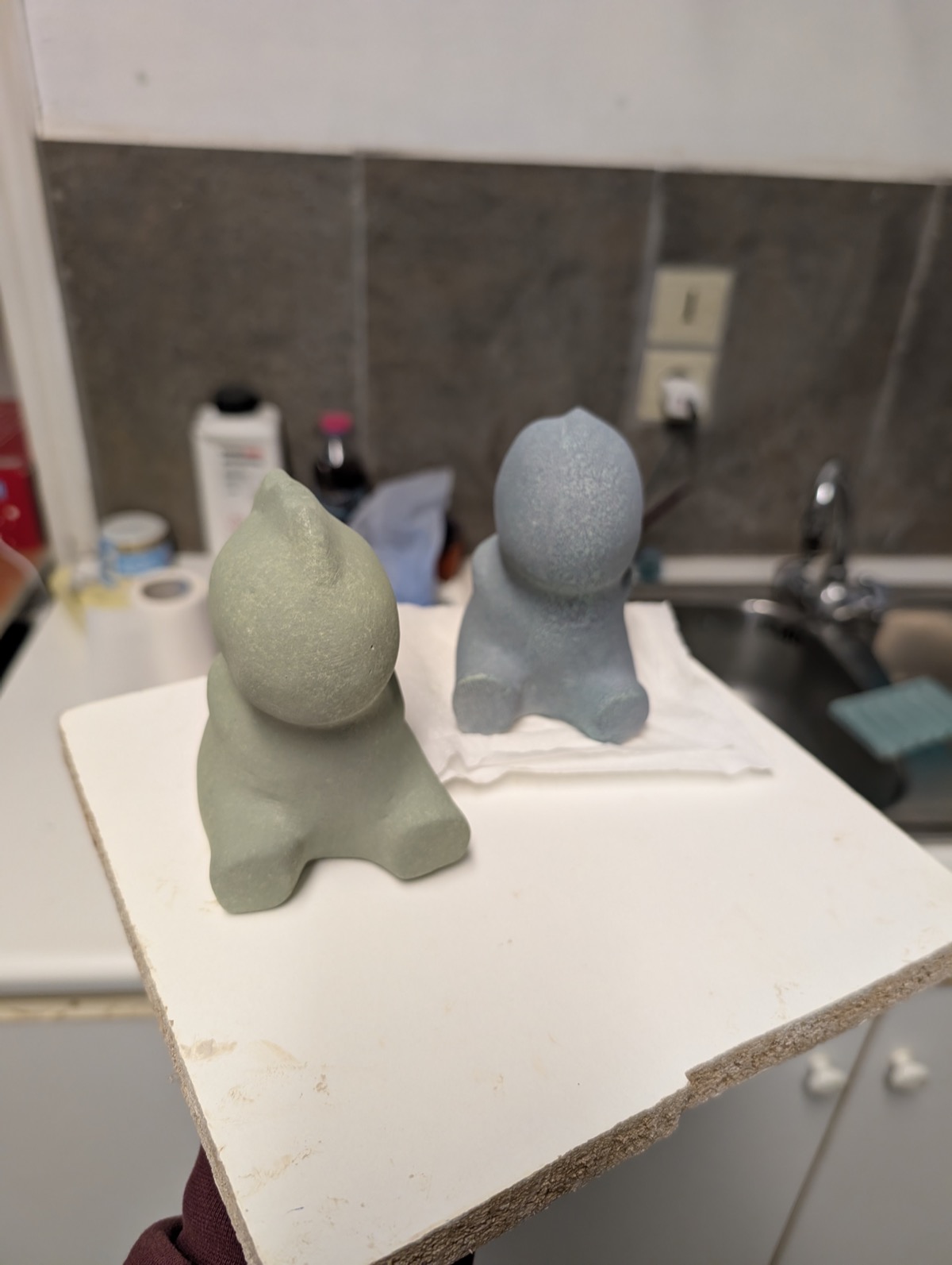 Two dinosaur figures just after being painted with underglaze from a cheap airbrush