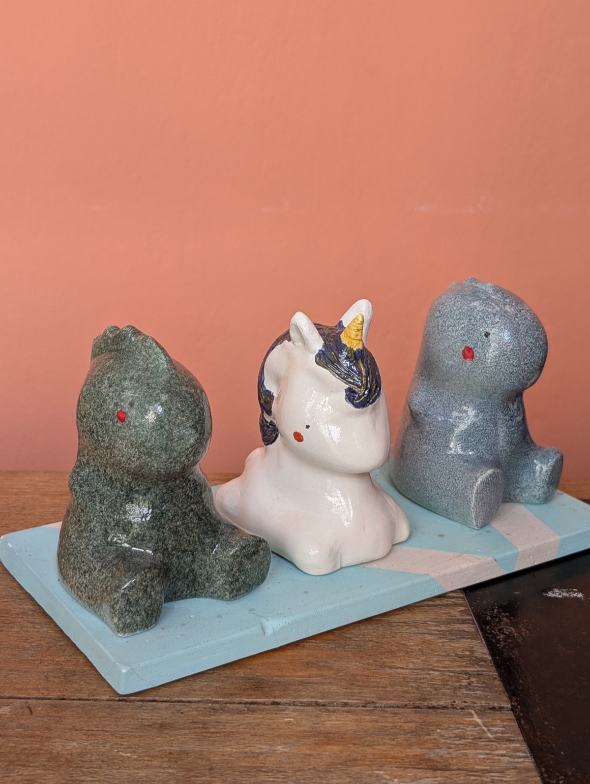 The three finished glazed figures, two dinosaurs and a unicorn, sitting together