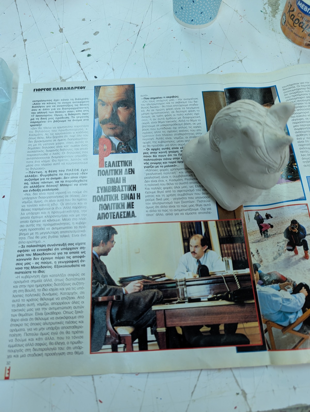 Unglazed clay unicorn shape resting on an old magazine, ready for sanding
